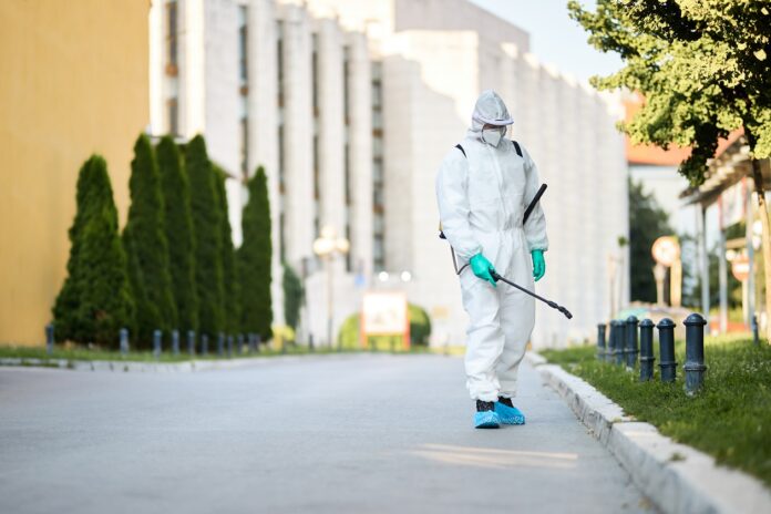 Man in protective suit disinfecting city streets during coronavi Pest Control Services
